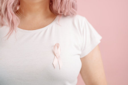 Woman in white T-shirt with pink satin ribbon symbolizing International Breast Cancer Day. october pink conceptの写真素材