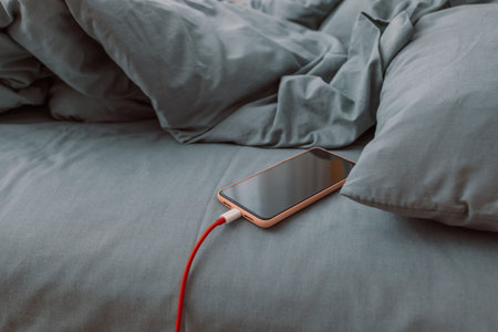 Mobile smart phone charging battery on bed in the bedroom at home. Technology, multiple sharing and...