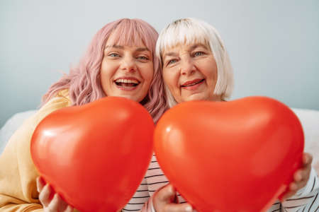 Two beautiful women in a good mood with red heart balloons happy smiling. Celebrating International Women Day, 8 march, mothers day, birthday.の写真素材