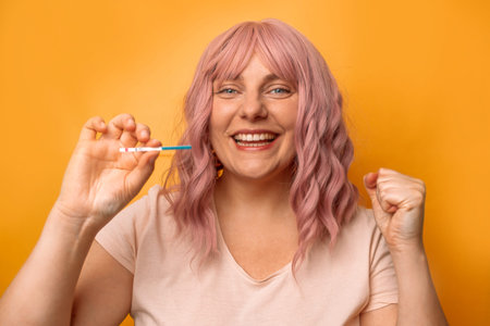 Happy young 30s woman holds a positive pregnancy test in her hand, long awaited pregnancy.