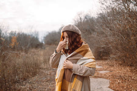 Sick young woman stand sneezing coughs feel sick at outdoor fever cold allergyの写真素材
