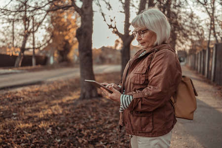 Happy dreamy older mature woman hand holding digital tablet with screen.の写真素材