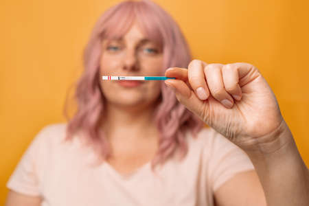 Happy young 30s woman holds a positive pregnancy test in her hand, pregnancy, womens health.の写真素材