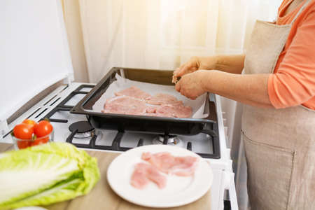 Chops. Woman hands put fresh turkey steaks meat on oven trayの写真素材