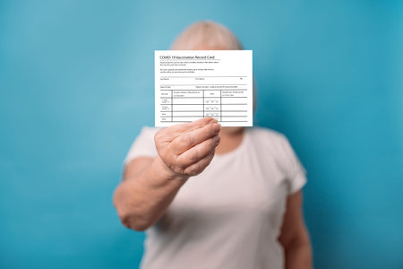 Vaccinated 50s old woman showing COVID-19 Vaccination Record Card after getting corona virus vaccine...