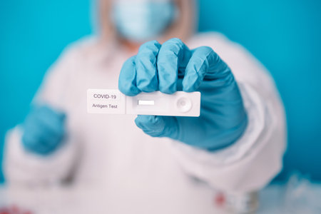 Doctor in blue gloves holding rapid antigen test kit with negative result during swab  testing over bright blue color backgroundの写真素材