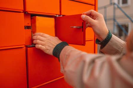 Pickup parcel. Putting carton box with shipping goods to self service postal case. Parcel shipping service or delivery packaging conceptの写真素材