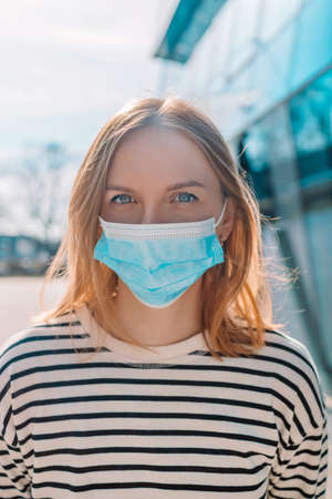Social Distancing 30s woman in city street wearing protective mask against disease virus SARS-CoV-2. Girl with face mask walks respecting social distancing during Pandemic virusの写真素材