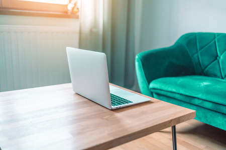 Laptop computer, house model on wooden table in sunny home office. Mortgage and real estate investment concept.の写真素材