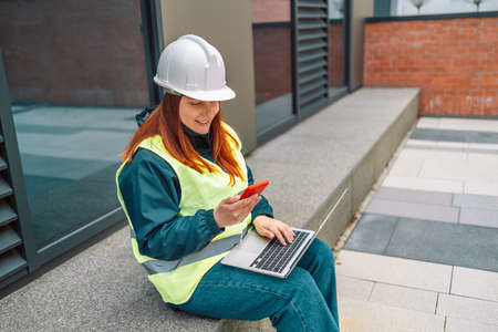 Hard working female construction engineer standing on a construction site. Confident engineer talking on the phone and show casing work in progressの写真素材