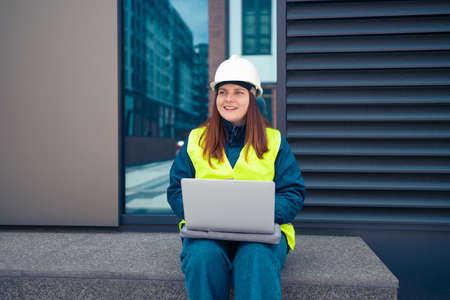 Construction woman worker engineer hardhat and safety vest with laptop at work on construction siteの写真素材