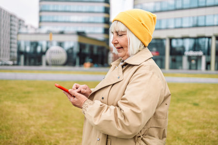 business woman 50 years old in stylish clothes using smart phone with hand finger touch screen,...