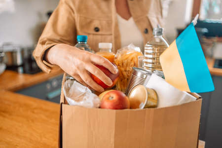volunteer packing the paper box with groceries and necessary things for Ukraine peopleの写真素材