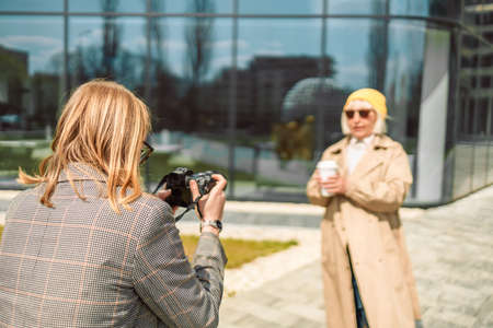 Professional female photographer take photo for women at business centre at morning time, private photo session and paparazzi.の写真素材