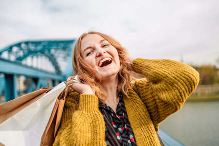 Close up of young 30s caucasian woman in dress smiling with teeth, looking at camera at city street. Positive emotions. Lifestyle concept.の写真素材