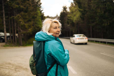 50s 60s senior woman traveler explorer with backpack hiking to the top of the mountain. Adventure weekend. High quality photoの写真素材