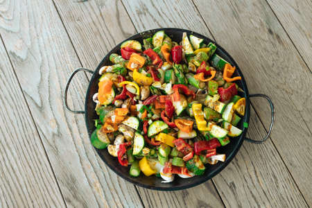Grilled vegetables in a pan on a wooden table in the backyard of the house at summer. Vegan, vegetarian, seasonal, healthy eating diet concept.の写真素材