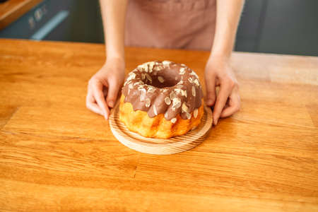 Woman chef cook in apron standing at the kitchen, showing tasty pie.の写真素材