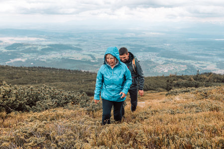 Poland, May 26 2022: Man and 50s woman hiking on wet rocks at mountain. Babia Gora Polandのeditorial素材