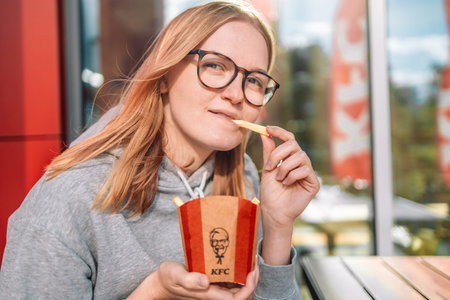 KFC fast food. Krakow, Poland - September 11 2022: Beautiful blonde woman is eating tasting french...