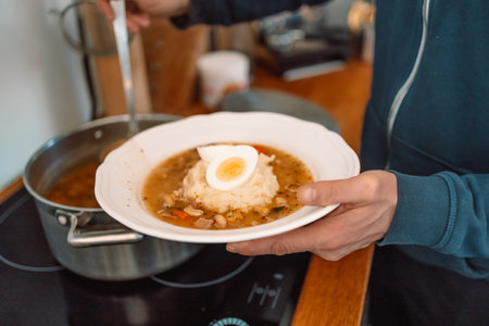 Man pouring Traditional Polish sour soup Zurek into a bowl.