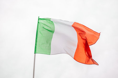 Italian national flag waving in the wind with blue sky used as backgroundの写真素材