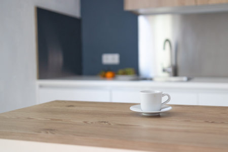 Cup of hot tea or coffee on a table in contemporary kitchen interior. Kitchen appliances and decor...