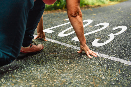 Numbers 2023 written on the road towards new goals in 2023 and female runners are starting to run....