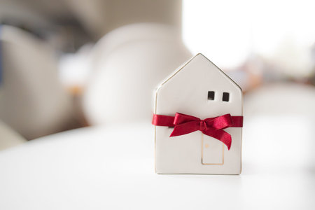 Merry Christmas and happy new year horizontal banner with small toy model house wrapped in red satin...
