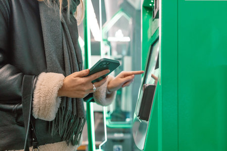 Close-up of a woman paying at a self-service machine using a contactless phone payment. Woman take a...
