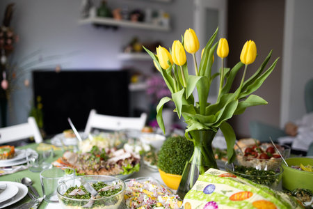 Home interior with easter decor. Spring flowers in a vases. Traditional Easter dishes with white...