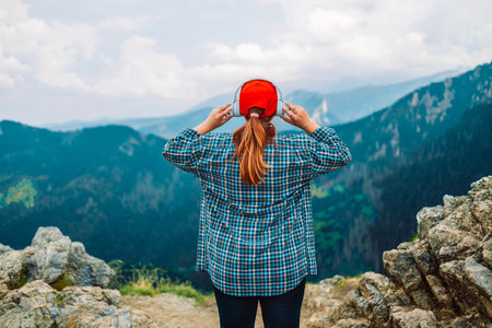 Woman in headphones listening music in nature and at the mountain, female tourist with long blond hair relax after walking enjoy journey trip, copy spaceの写真素材