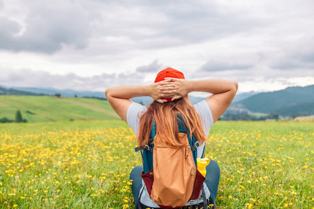 Young woman on the Tatry mountain peak with green grass looking at beautiful mountains in summer. Colorful landscape with lying girl, forest, hills, sky. Travel and tourismの写真素材