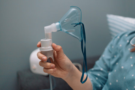 Portrait of young sick woman putting on nebulizer mask on face to make inhalation, using an inhaler...