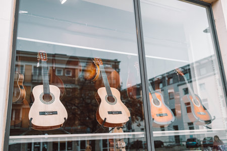 Gdansk, Poland - November 11, 2022: Acoustic guitars of different colors and types on a musical instrument store window. Foreground. Selective focusのeditorial素材