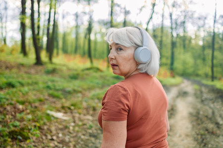 Fitness, health and a running senior woman on a road through a forest or park for cardio and...