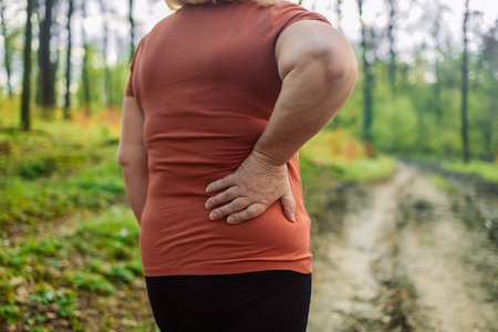 Tired senior 50s 60s athlete runner exhausted of cardio workout breathing hard after difficult exercise in a park. Caucasian fitness woman running s muscle back pain or cramps. High quality photoの写真素材