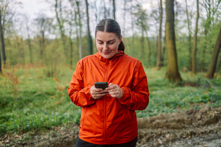 Side view of young female traveler with backpack and in warm wearing standing in the spring forest...