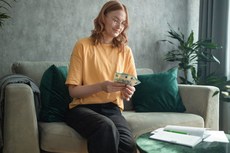 Young blonde female work with financial papers at home count on calculator before paying taxes...