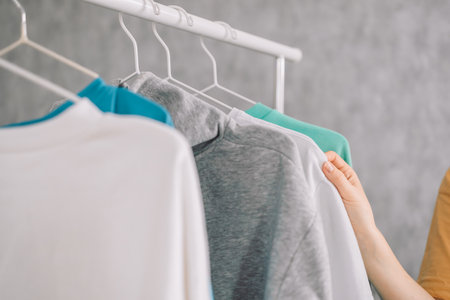 Wardrobe rack with stylish clothes near white wall indoors. Space for text. High quality photoの写真素材