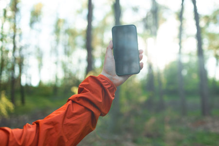 Woman stands in a autumn forest on a hike and catches a phone call on a smartphone with his arm...