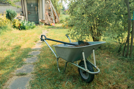 garden cart with earth and a shovel stands on the lawnの写真素材