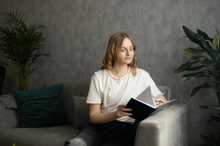 Thoughtful and cozy blonde 30s woman sitting taking notes on notebook. Relaxation lifestyle concept