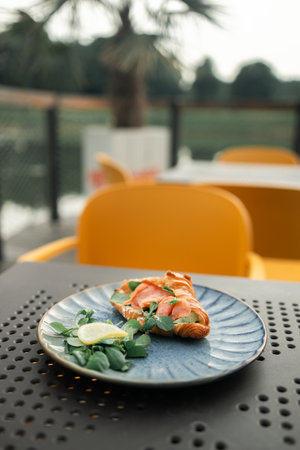 Croissant sandwich with salmon, poached egg and cucumber on plate. Breakfast in cafe or coffee shop. Lifestyles. High quality photoの写真素材