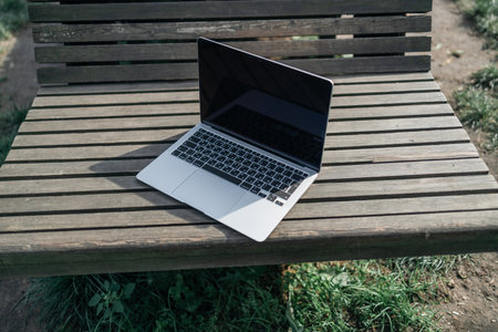 Laptop and nature. Laptop on a wooden table surrounded by forest. Close-up. High quality photoの写真素材