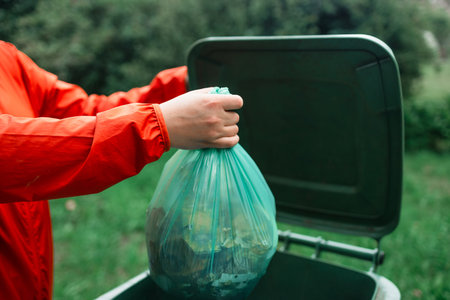 Caucasian woman sorting garbage, throwing a used paper bag in a small recycle bin at outdoor near a home . High quality photoの写真素材