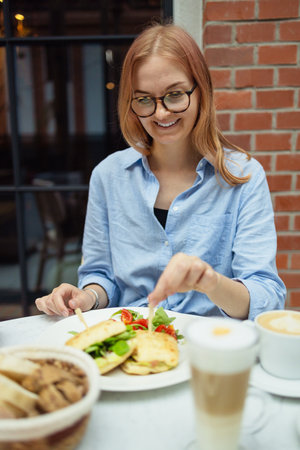 Woman eating breakfast. Healthy chicken and spinach sandwiches and fresh vegetable salad on the table at city cafe. Healthy diet food concept. for breakfast or lunch. Vegetarian food.の写真素材