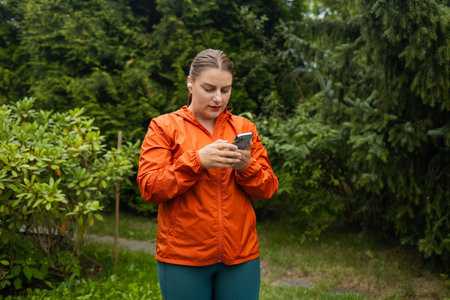 30s young amazing sports fitness woman outdoors listening music with earphones using mobile phone....