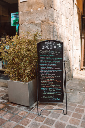 Black Restaurant menu chalkboard on the street. A menu chalkboard with a list of dishes in front of a restaurant in a pedestrian street in Pisa, Italy. High quality photoの写真素材