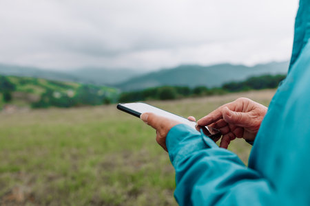 Young woman hand with smartphone catching signal at mountains. Road trip, transport, travel, technology and people concept. High quality photoの写真素材